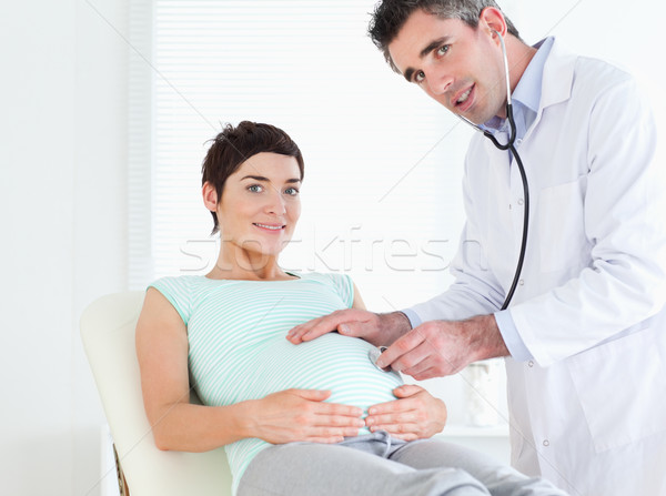 Doctor examining a tummy with a stethoscope in a room Stock photo © wavebreak_media