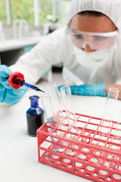 Stock photo: Portrait of a protected scientist dropping blue liquid in a test tube in a laboratory