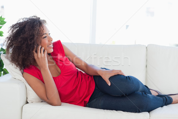 A smiling woman making a phone call while she lies on the couch. Stock photo © wavebreak_media