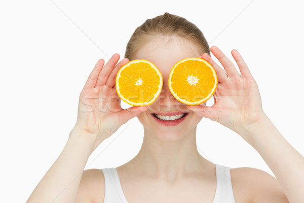 Smiling woman placing oranges on her eyes against white bakground Stock photo © wavebreak_media