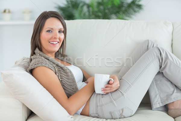 Femeie zambitoare canapea cană camera de zi femeie Imagine de stoc © wavebreak_media
