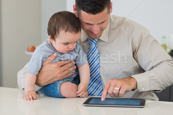 Stock photo: Businessman using tablet while holding baby