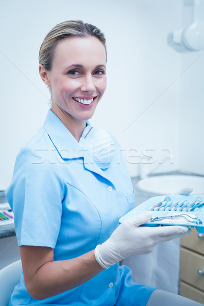 Stock photo: Female dentist in blue scrubs holding tray of tools