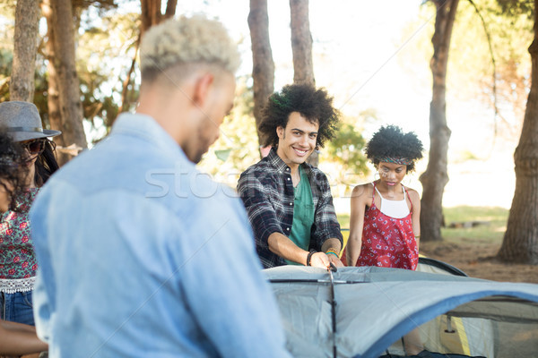 Stock photo: Smiling man with friends setting up tent