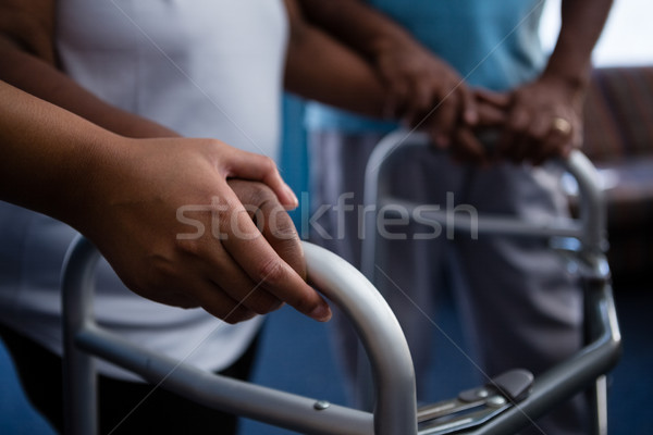 Stock photo: Cropped hands of nurse assisting woman in walking with walker