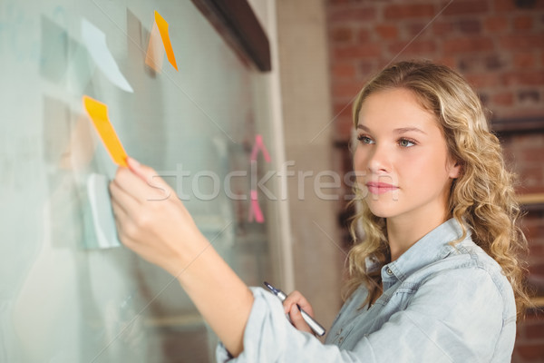 Beautiful businesswoman sticking notes on board in office  Stock photo © wavebreak_media