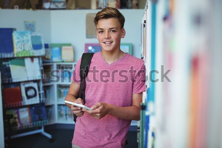 Portrait of happy schoolboy holding digital tablet in library at school Stock photo © wavebreak_media