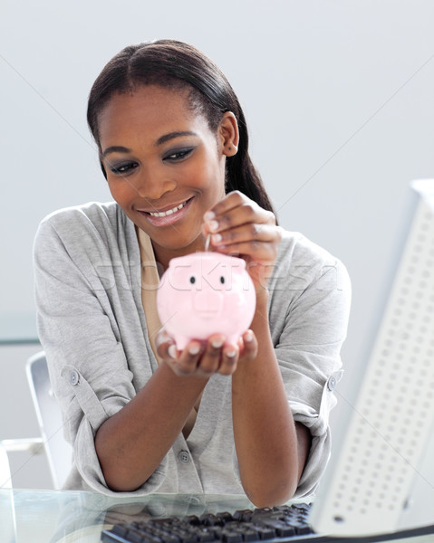 Assertive Afro-american businesswoman saving money in a piggyban Stock photo © wavebreak_media