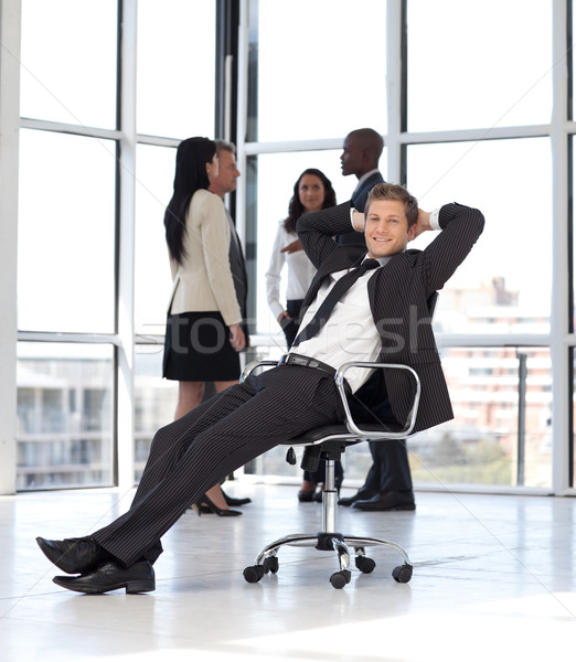 Stock photo: manager relaxing in office with team in background 