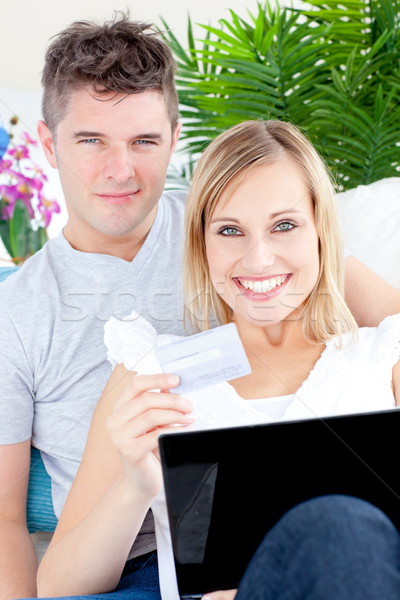 Enamored couple lying on the sofa with a laptop and a card at home Stock photo © wavebreak_media