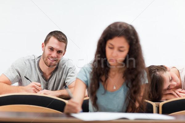 Smiling students writing while their classmate is sleeping in an amphitheater Stock photo © wavebreak_media