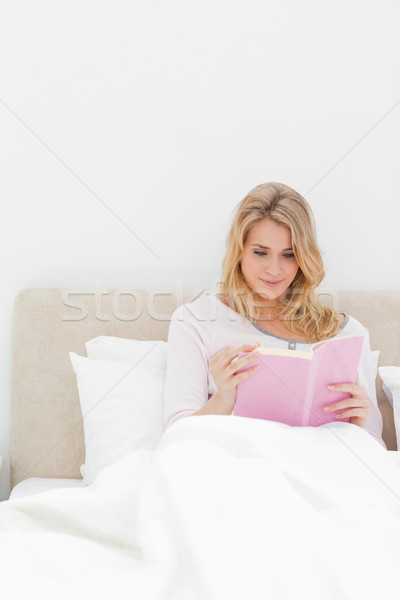 A closer shot of a woman in bed sitting upright as she reads her book. Stock photo © wavebreak_media