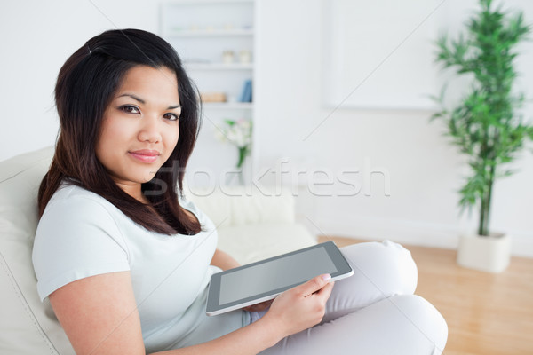 Woman sitting on a sofa while holding a tactile tablet in a living room Stock photo © wavebreak_media