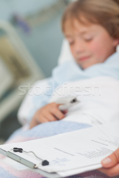 Stock photo: Focus on medical result next to a child in hospital ward