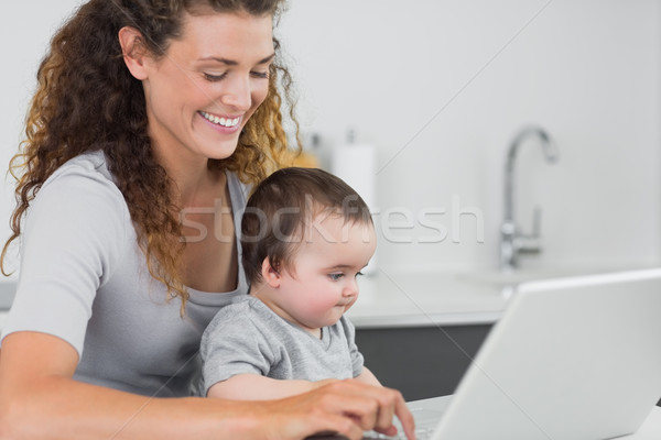 Smiling woman with baby using laptop  Stock photo © wavebreak_media