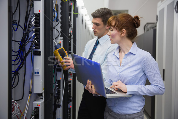 Stock photo: Team of technicians using digital cable analyser on servers