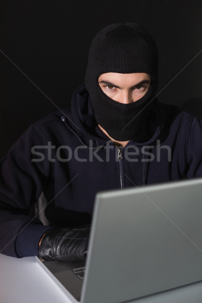 Scassinatore seduta l'hacking laptop guardando fotocamera Foto d'archivio © wavebreak_media