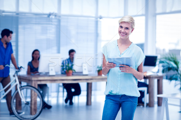 Stock photo: Pretty businesswoman holding a tablet in the office