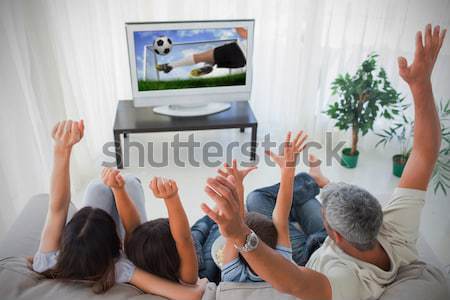 Composite image of family raising their arms in front of televis Stock photo © wavebreak_media