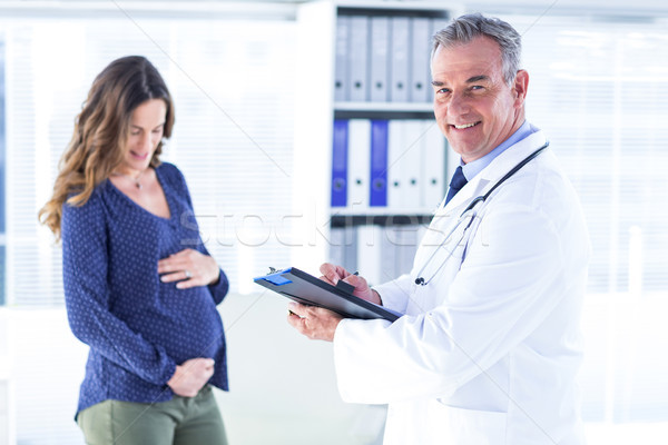 Stock photo: Male doctor with pregnant woman in clinic