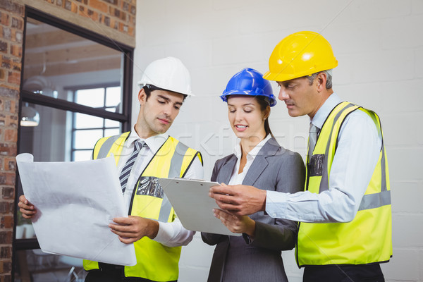 Architect team discussing while holding blueprint and clipboard  Stock photo © wavebreak_media