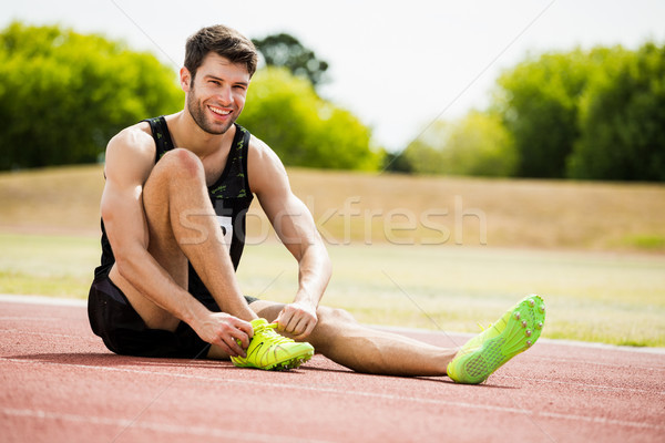 Stock photo: Athlete tying his shoe laces on running track