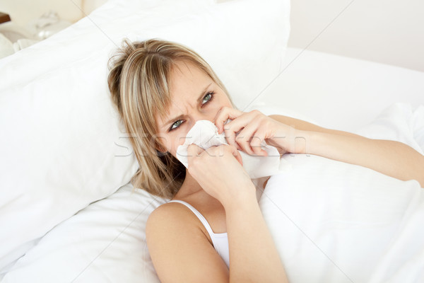 Sick young woman blowing lying on her bed Stock photo © wavebreak_media