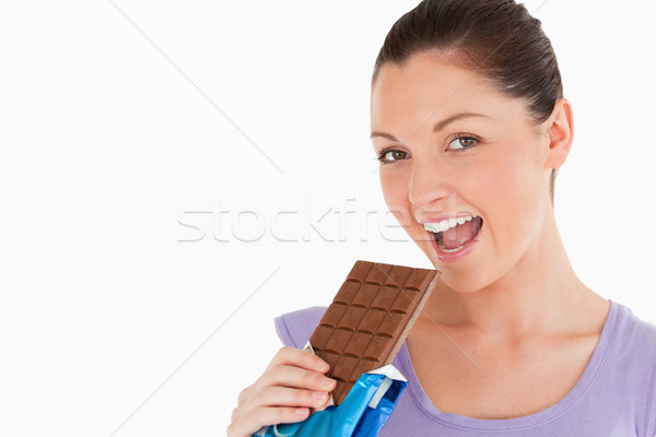 Portrait of a good looking woman eating a chocolate block while standing against a white background Stock photo © wavebreak_media