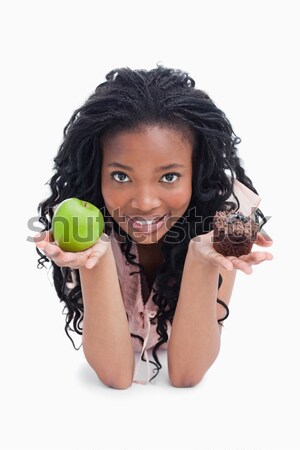 A young woman is choosing between an apple or a bun against a white background Stock photo © wavebreak_media
