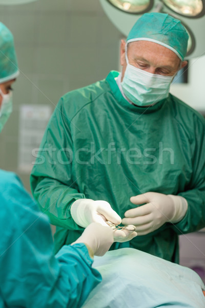 Surgeon giving a scissors to an other surgeon in a surgical room Stock photo © wavebreak_media