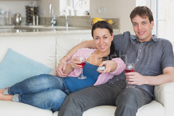 Stock photo: Young couple sitting on the couch and drinking wine while watching television