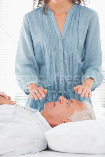 Therapist performing Reiki over face of man Stock photo © wavebreak_media