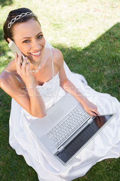 Happy bride with laptop using cellphone on grass Stock photo © wavebreak_media