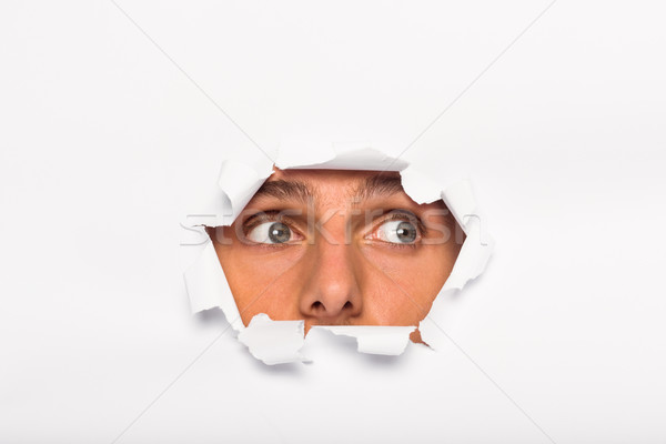 Young man looking through paper rip Stock photo © wavebreak_media