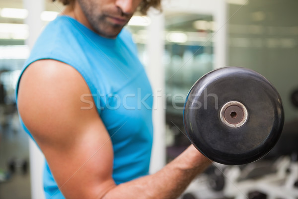 Stock photo: Mid section of man exercising with dumbbell in gym