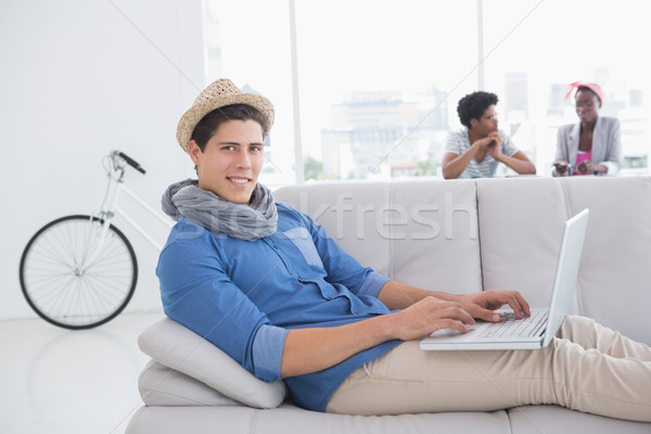Young creative man using laptop on couch Stock photo © wavebreak_media