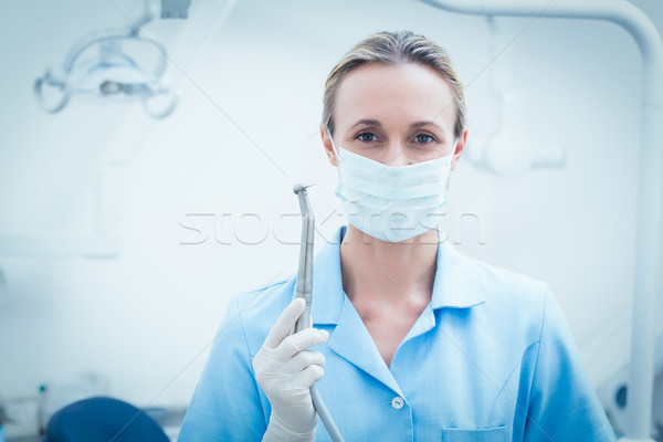 Female dentist in surgical mask holding dental tool Stock photo © wavebreak_media