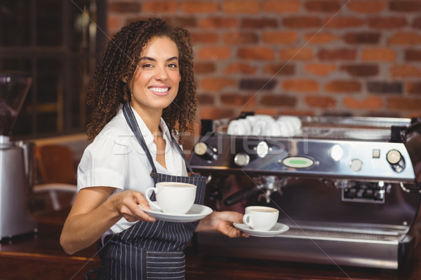 Stock photo: Smiling barista holding two cups of coffee