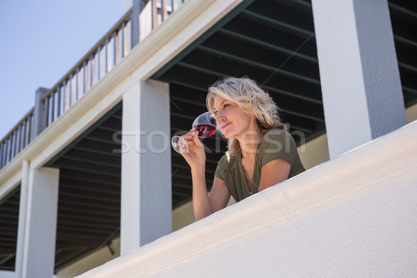 Mid adult woman drinking red wine while standing in balcony at restaurant Stock photo © wavebreak_media