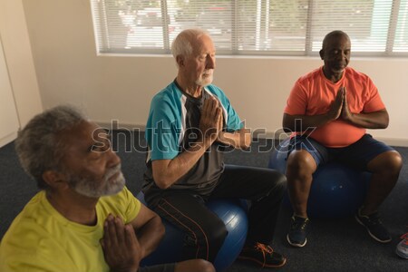 Stock photo: Physiotherapist maintaining record of senior woman performing exercise on fitness ball