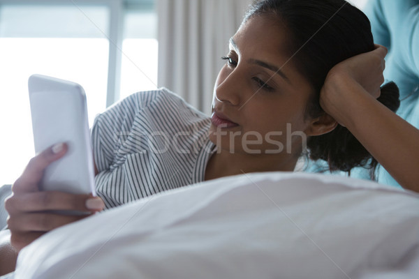 Woman using phone while resting on bed Stock photo © wavebreak_media