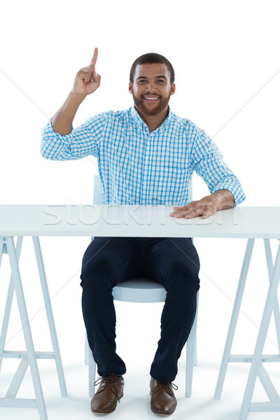Stock photo: Male executive pointing upwards while sitting at desk