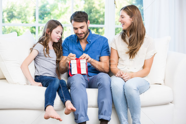 Man opening gift while sitting on sofa with family Stock photo © wavebreak_media