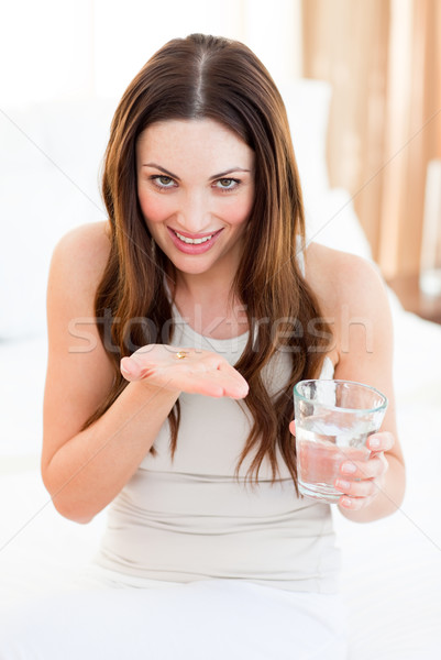 Stock photo: Brunette woman taking a pill sitting on bed