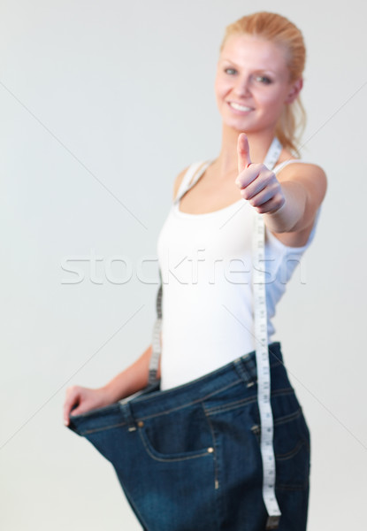 Portrait of a woman with thumb up wearing big jeans focus on thumb Stock photo © wavebreak_media