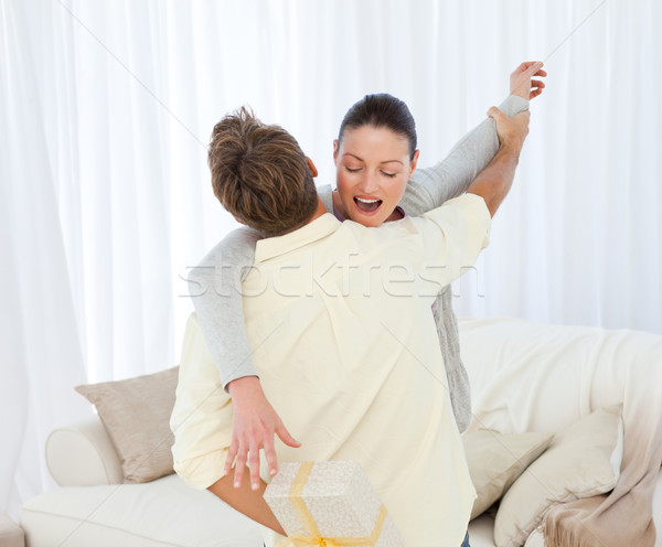 Excited woman catching a present hidden behind her boyfriend in the living room Stock photo © wavebreak_media