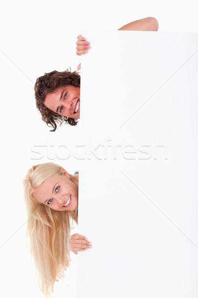 Couple hiding behind a whiteboard in a studio Stock photo © wavebreak_media