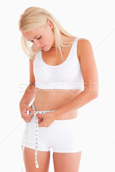 Stock photo: Woman measuring her waist in a studio