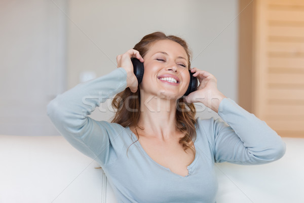 Mosolyog fiatal nő élvezi zene kanapé fejhallgató Stock fotó © wavebreak_media