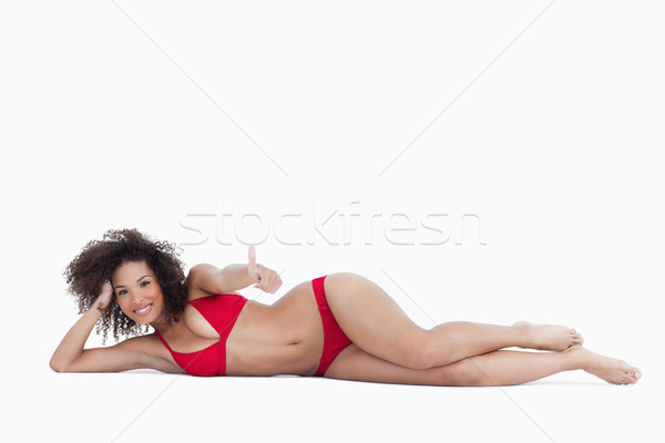 Smiling woman lying down while placing her thumbs up against a white background Stock photo © wavebreak_media
